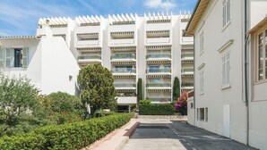 A modern multi-story building with balconies, a central courtyard, and surrounding greenery.