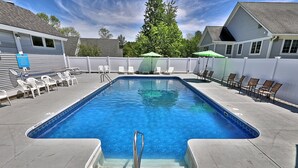 A rectangular swimming pool with a metal ladder, surrounded by white and brown lounge chairs, and a white fence. - Charming Killington Studio w/ Pool. Bus Route. Ski Rental Deals! - Killington Center Suites 131 (Killington)