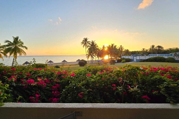 Sunset over the beach with tiki huts.