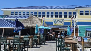 A beachside restaurant with outdoor seating and a thatched roof structure. - Tropical Isle 215 - Steps to the Beach! (Fort Walton Beach)