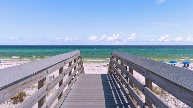 A wooden boardwalk leading to a sandy beach with a clear view of the ocean. - Tropical Isle 215 - Steps to the Beach! (Fort Walton Beach)