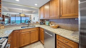 A modern kitchen with wooden cabinets, granite countertops, and stainless steel appliances.