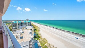 A high-rise hotel overlooking a beach with clear turquoise waters.