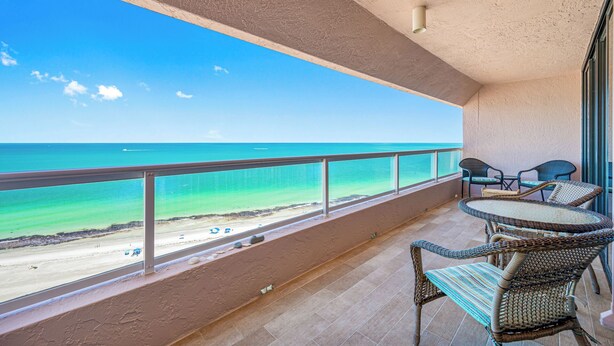 A balcony with a view of the beach and ocean.