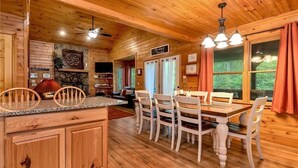 A wooden cabin interior with a dining area, kitchen, and a fireplace. - Legacy Lodge Cabin-Near Helen,GA Hot Tub,Screened deck, Tubing,Hiking,Loft (Sautee Nacoochee)