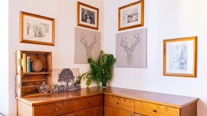 Un mobiletto in legno con diversi cassetti e ripiani, decorato con quadri incorniciati e una pianta in vaso.
