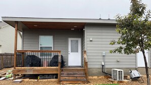 A single-story house with a covered porch, a front door, and a small front yard with artificial grass. - Frida's Tiny Home (San Antonio)