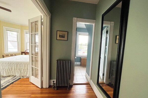 A room with a bed, a radiator, and a large mirror.