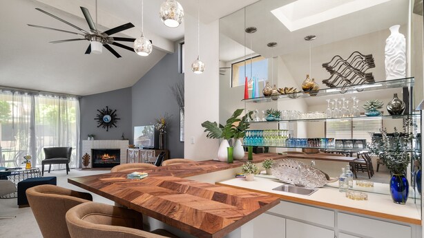 A modern kitchen with a wooden island, a built-in sink, and a dining area with chairs.