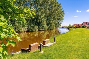 Ein Park am Flussufer mit hölzernen Bänken und einer Rasenfläche.