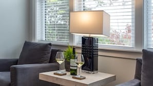 Un salon moderne avec un canapé, une table basse, une lampe et deux verres de vin blanc.