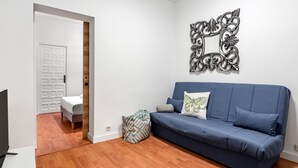 En moderne stue med en blå sofa, en pude med mønster og et dekorativt spejl på væggen.