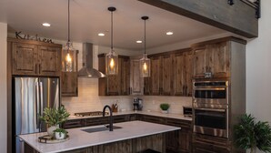 Una cocina moderna con armarios de madera, electrodomésticos de acero inoxidable e iluminación colgante.