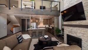 Un amplio salón con techo alto, una cocina equipada con electrodomésticos modernos y una chimenea.