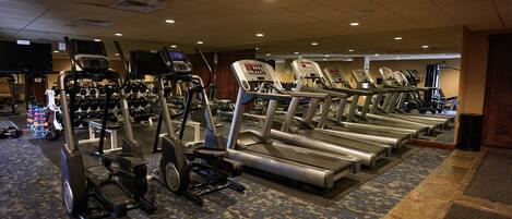 A gym with treadmills, elliptical machines, and free weights.