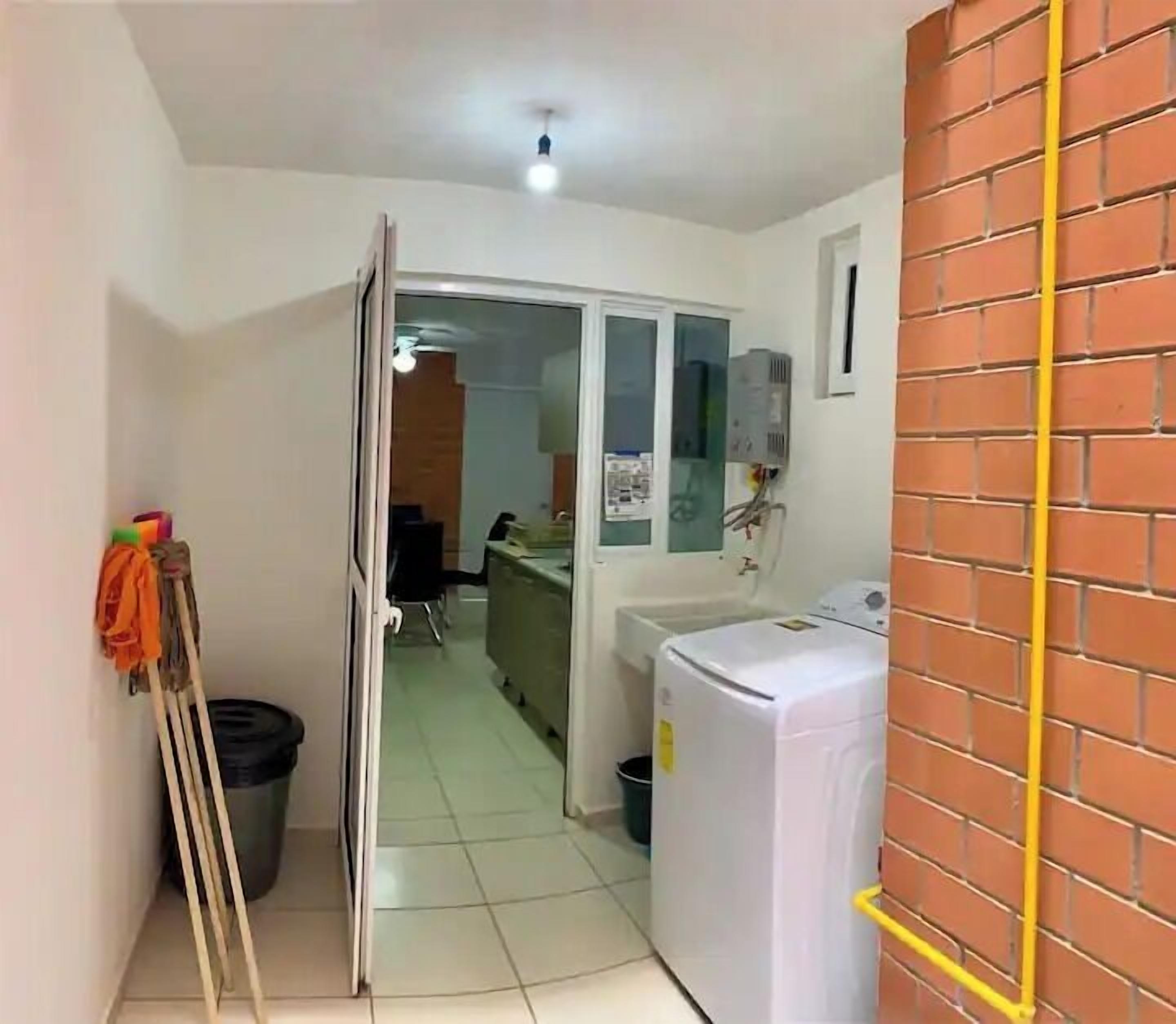 A laundry room with a washing machine, a dryer, and a trash bin.