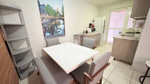 A dining area with a table and chairs, a kitchen in the background, and a cityscape painting on the wall. -  Torre Federacion 201 Zona Centro Guadalajara (Guadalajara)