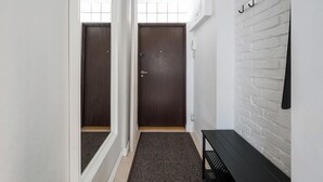 Un pasillo con una puerta de madera oscura, una pared de ladrillo blanco y un banco negro.