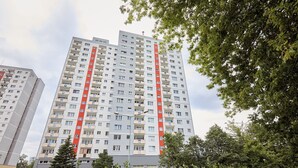 A high-rise residential building with multiple balconies and a red vertical stripe.