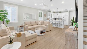 Una sala de estar moderna con un sofá color beige, una mesa de centro redonda y un televisor sobre un mueble de madera.