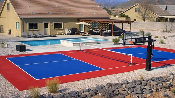 Un espace piscine avec un court de tennis et des chaises longues.