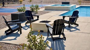 Une terrasse extérieure avec des fauteuils Adirondack, un foyer et une piscine.