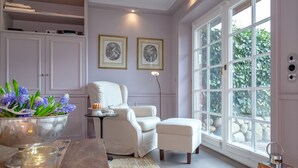 A cozy room with a large window, a white armchair, a small table with a candle, and a bowl of flowers. - Weetstich - Willkommen im Weetstich in Archsum (Archsum)