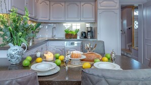 A modern kitchen with white cabinetry, a coffee machine, and a dining area with a table set for two. - Weetstich - Willkommen im Weetstich in Archsum (Archsum)
