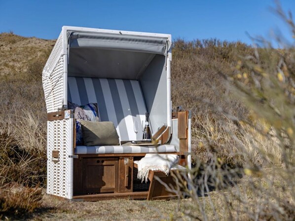 A beach chair with a striped cushion, a small table, and a wooden bench.
