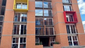 Een meerlaags gebouw met een bakstenen gevel, meerdere balkons en grote ramen.