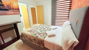 Een slaapkamer met een bed, nachtkastje, dressoir en een schilderij aan de muur.