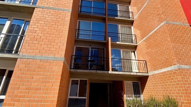 A multi-story building with a red brick facade, multiple balconies, and a clear sky. - Torre Federacion 602 Zona Centro Guadalajara (Guadalajara)