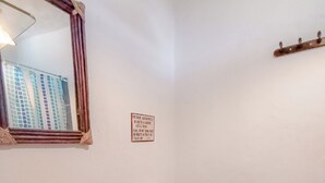A bathroom with a white sink, a toilet, and a mirror. There is a sign on the wall and a towel dispenser. - Aloha Lina (Máncora)