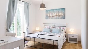 A bedroom with a bed, bedside tables, a desk, and a window with curtains. - Lovely home in Smoljanci (Smoljanci)