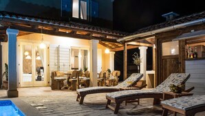 A covered outdoor area with lounge chairs, a pool, and a dining area with tables and chairs. - Lovely home in Smoljanci (Smoljanci)