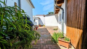 A narrow brick pathway leading to a white building with a wooden fence and potted plants. - De Lütte Seileree - de Lütte Seileree - Ein Sicherer Hafen und Rückzugsort für Hund und Mensch (Heringsdorf)
