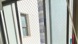 A bathroom with a window, an ironing board, a mop, and a broom. - Pérola do Aquarius IV (São José dos Campos)