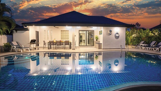 Ein modernes Hotel mit Pool, Essbereich und Blick auf den Sonnenuntergang.