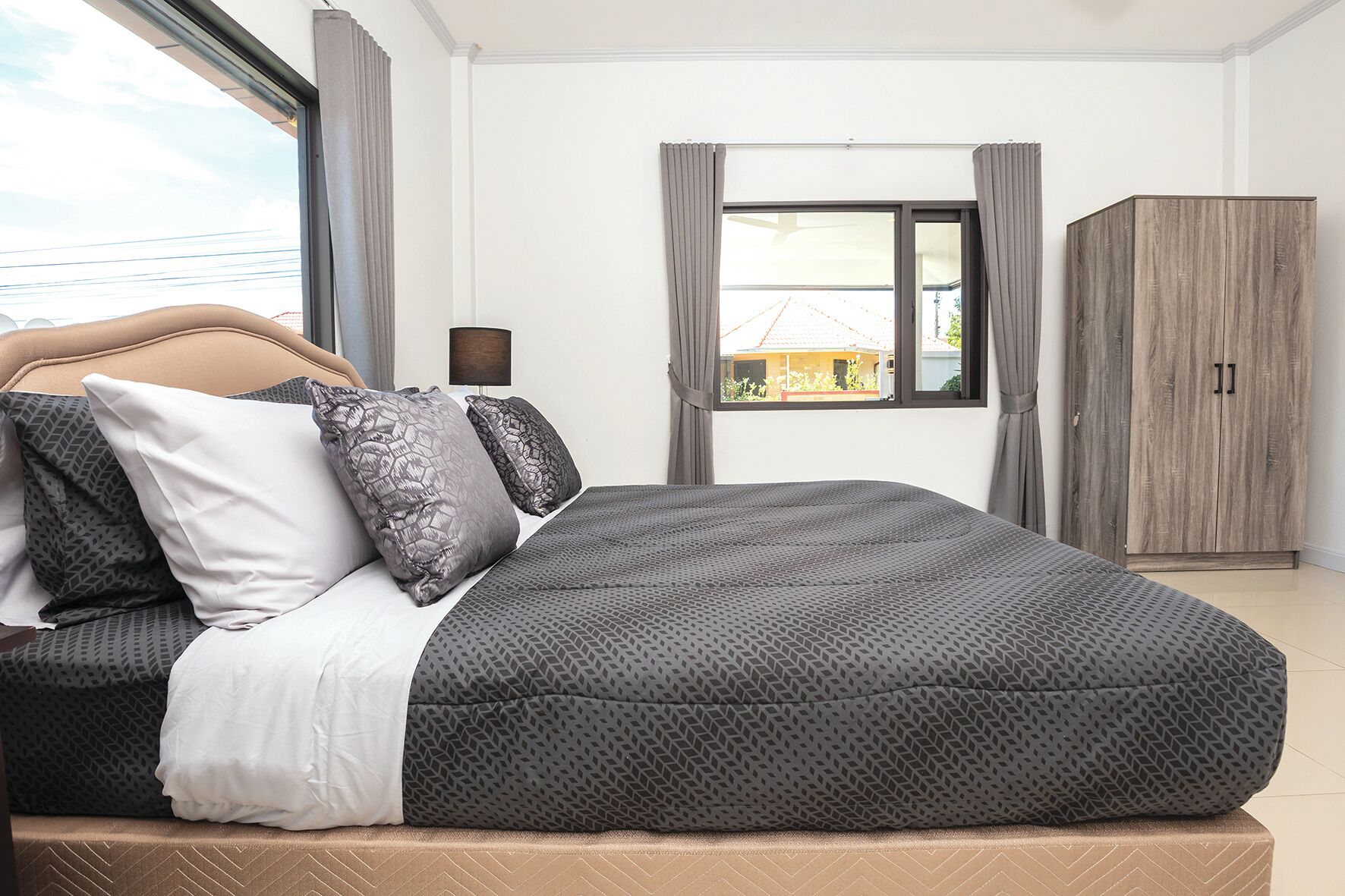Un dormitorio con cama, armario y ventana con cortinas.