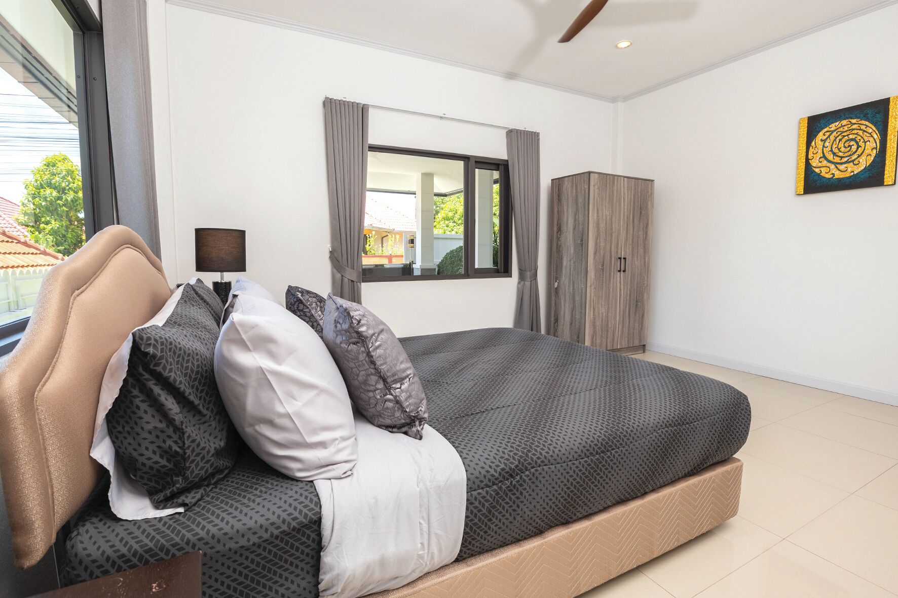 A modern bedroom with a bed, a wardrobe, and a window with curtains.