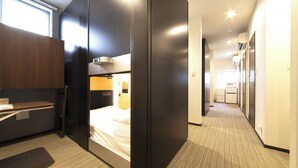 Ein modernes Hotelzimmer mit Bett, Schreibtisch und Kleiderschrank.