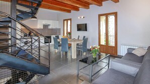 A modern kitchen with white cabinets, a dining area with a table and chairs, a staircase with metal railings, and a living area with a sofa and a coffee table. - Amazing home in Privas with sauna (Privas)