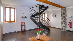 A spacious room with a modern staircase, a stone pillar, and a wooden table with a vase of flowers. - Amazing home in Privas with sauna (Privas)