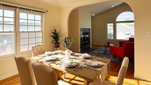 Un coin repas avec une table dressée pour quatre personnes, une cheminée et une vue sur un véhicule par la fenêtre.