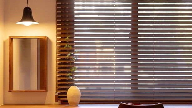 Una habitación con un escritorio de madera, un espejo, un florero y una silla.