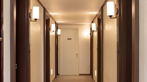 Un pasillo de hotel con varias puertas, cada una con una lámpara encima.