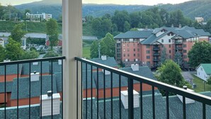 Un balcon donnant sur un quartier résidentiel, avec des immeubles à plusieurs étages et, au loin, un paysage vallonné.