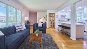 Ein modernes Wohnzimmer mit Sofa, Couchtisch und Blick auf die Küche.