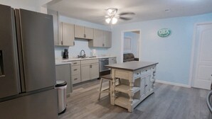 Een moderne keuken met een centraal eiland, roestvrijstalen apparatuur en lichtblauwe wanden.