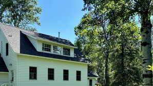 A two-story white house with a sloped roof, a front porch, and a well-maintained lawn.